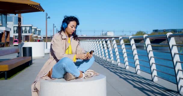 Footage Young Asian Woman Meditates Embankment She Sits Headphones Listens — Stock video