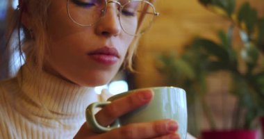 A young woman drinking tea at a cafe. Slow motion 4k footage. Close-up.