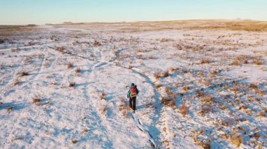 Aerial view of a lonely human walking through snowy desert. Extreme tourism and the concept of survival in extreme cold conditions.