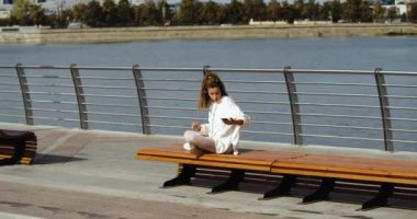 Zoom in of a young woman puts down her smartphone and start meditating - she is listening to the calm music and resting from city noise and daily bustle. Urban lifestyle. Urban lifestyle. 4k footage.
