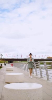 Great news - Caucasian woman with a smartphone in her hand is jumping with happiness. Urban scene outdoor. Slow motion vertical 4k footage.