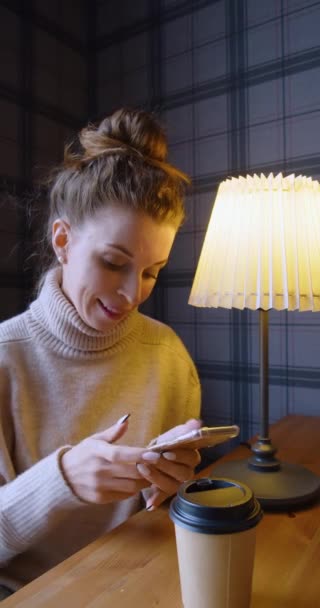 30歳の女性は スマートフォンを通じてボーイフレンドとオンラインメッセージを通信します 彼女は愛にあり 彼女が彼女の夢の男に会ったことを非常に満足している 縦4K映像 — ストック動画