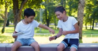 Two brothers - older one prevents the younger one from playing on the tablet computer and tries to take away the tablet. Concept of modern children addictions. 4k footage.