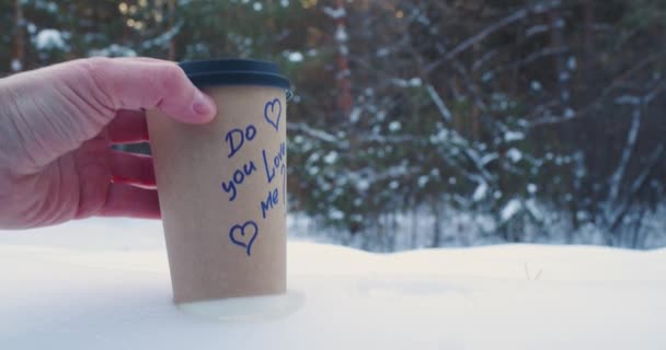 Αρσενικά Και Θηλυκά Χέρια Βάζουν Χάρτινο Κύπελλο Καφέ Στο Χιόνι — Αρχείο Βίντεο