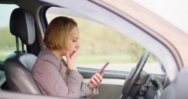 A 40-year-old woman receives a message while driving a car and becomes insanely upset. She drops her head on the steering wheel in shock.