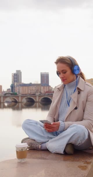 Young Woman Meditates Embankment She Sits Headphones Listens Relaxing Music — Vídeo de Stock