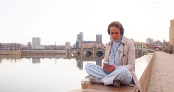 Uma Jovem Medita Dique Ela Senta Fones Ouvido Ouve Música — Vídeo de Stock