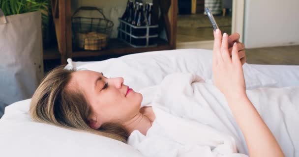 Жінка Лежить Ліжку Смартфоном Вона Перевіряє Соціальні Медіа Після Пробудження — стокове відео