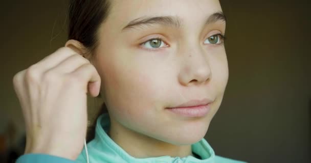 Ένα 10Χρονο Κορίτσι Βάζει Ακουστικά Κοιτάζει Την Κάμερα Και Χαμογελάει — Αρχείο Βίντεο