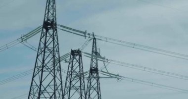 High-voltage transmission towers against the blue sky. The concept of radiation and induction field around high voltage cables. 4k footage.