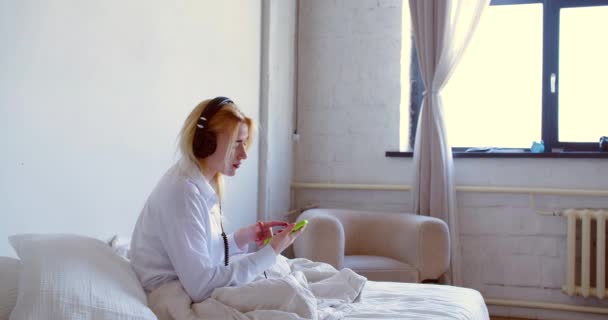 Кадри Молодої Жінки Прокинулися Слухають Музику Через Навушники Додатком Онлайн — стокове відео