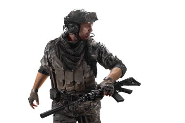 A mercenary soldier walks with an automatic rifle in his hand and looks away. A professional special forces soldier during a special operation. Isolated on a white background.