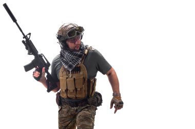 Walking ercenary soldier with an automatic rifle in his hand. Professional special forces soldier walking and looking by side during a special operation. Photo isolated on white.