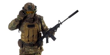 A professional mercenary soldier during a special operation. He calls for support on the radio while looking at the camera. Photo with copy space on white background.