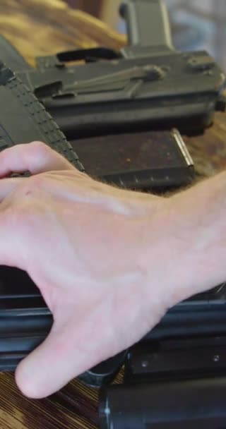 一个男性手的特写镜头把卡拉什尼科夫冲锋枪放在一张木制桌子上 准备战斗 慢动作垂直4K镜头 — 图库视频影像
