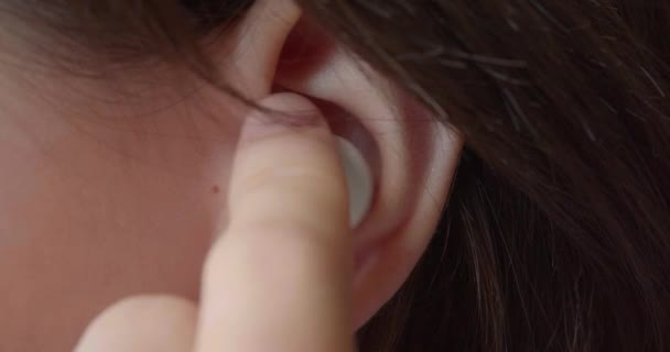 插入耳机的特写 一个少女的耳朵 她放了一个小耳机听音乐 现代青年及其文化 Clsoe Up慢动作4K镜头 — 图库视频影像