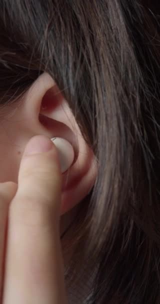 插入耳机的特写 一个少女耳朵的垂直录像 她放了一个小耳机听音乐 现代青年及其文化 特写慢镜头4K — 图库视频影像