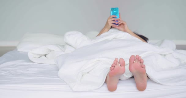 Vrouw Bed Met Haar Benen Naar Camera Gericht Geabsorbeerd Smartphone — Stockvideo