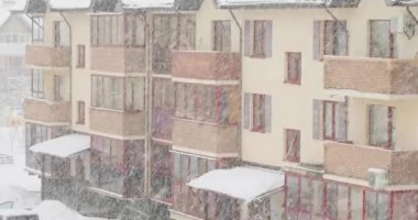 Banliyöde kar fırtınası. Küçük tipik kasaba evlerinin penceresinden 4K video. Yavaş çekim 4k görüntü.