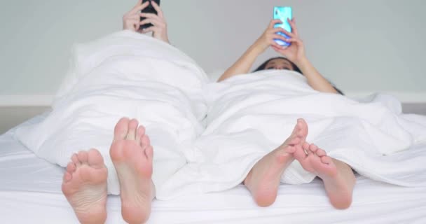 Para Leżąca Łóżku Nogami Zwróconymi Aparatowi Pochłonięta Ekranem Smartfona Uzależniający — Wideo stockowe