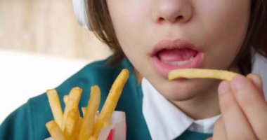 Gençlerin abur cubur bağımlılığı. Fast food zımbası kullanan genç bir kız. Patates kızartması. Bu kadar sağlıksız yiyecekler tüketmenin zararlı etkileri özellikle gençler için vurgulanıyor. Yakın çekim görünümü