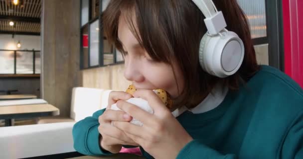Uma Adolescente Fones Ouvido Come Hambúrguer Vício Juvenil Alimentos Não — Vídeo de Stock