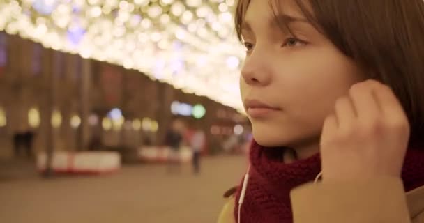 一个少女插入耳机 在智能手机应用程序上选择音乐 以及欣赏圣诞气氛的特写视频 — 图库视频影像