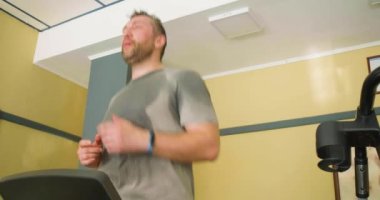 Orta yaşlı bir adam koşu bandında koşar. 40 'larında formda kalıyorsun. Yavaş çekim 4k görüntü.