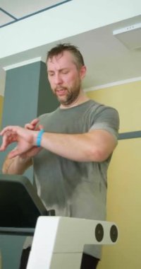 Orta yaşlı bir adam akıllı saatine bakar ve eğitim sürecini ayarlar. Modern teknolojiyle eğitime akıllıca bir yaklaşım. Yavaş çekim dikey 4k görüntü.