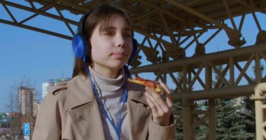 Endişelerinizi unutun ve en sevdiği melodileri dinlerken aromatik kahve ve lezzetli pizzanın tadını çıkaran bir ergenle anın tadını çıkarın. Şehir eğlencesi ve kaygısız gençlik. 4k görüntü.