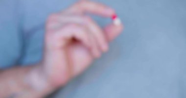 Kırmızı ve beyaz kapsül bir insanın elinde. Aşısız virüslerin tedavisinde kullanılacak ilaçlar ve ilaçlar..