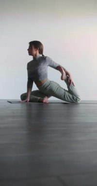 Yoga ve meditasyon, güvercin pozu. Genç bir kadın yoga yaparak huzurunu geri kazanmak için kendini gözden uzak tuttu. Dikey 4k görüntü.