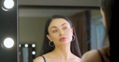 Kafkasyalı genç bir kadının evdeki aynanın önünden makyaj vakfı uygulamasını yakınlaştır. Yavaş çekim 4K video. Yakınlaştır.