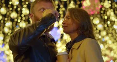 Aşk, kahve ve Noel gecesi. Noel arifesinde sokakta kucaklaşan orta yaşlı bir çiftin yakın çekim videosu. Yavaş çekim 4k video.