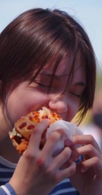 Kaldırımdaki kafede hamburger yiyen genç bir kızın 4K videosunu büyüt..