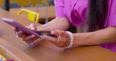 Akıllı telefon ve kredi kartı olan bir kadının yakın çekim görüntüsü. Kaldırımdaki kafede kahve molası sırasında internetten alışveriş. Yavaş çekim 4k görüntü.