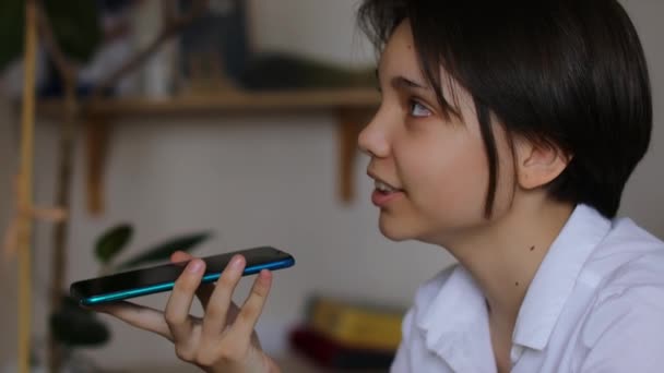 12歳の女の子は自宅の快適さからの距離に通信するための技術の力を受け入れ 彼女のスマートフォンに音声メッセージを記録します — ストック動画
