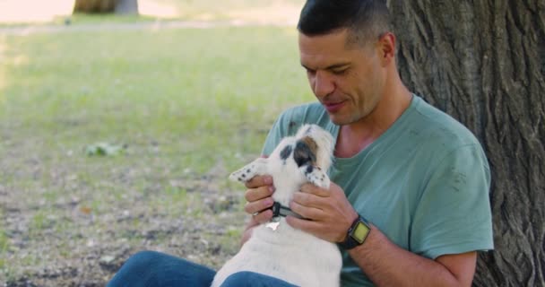 男と親友 心の健康への道としてペットへの愛 中年の男がジャック ラッセル テリアの犬と屋外で遊ぶ ズームアウト4Kビデオ — ストック動画