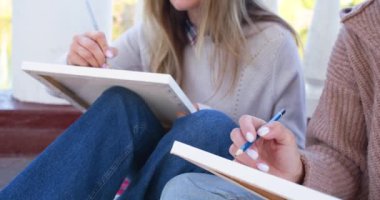 Kadınlar açık havada resim yapar. Küçük bir kadın sanatçı grubu resimlerini doğada çiziyor. Sanat yoluyla psikolojik rahatlama ve güzelliğin yaratılması. Kalem kapaklı kadın elleri..