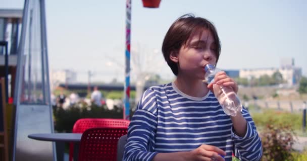 在一个温暖的夏天 少女坐在人行道上的咖啡店里喝水 慢动作4K镜头 — 图库视频影像