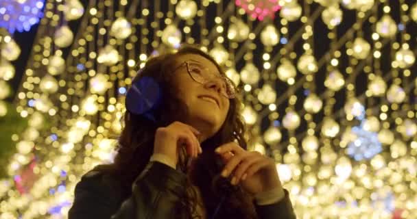 크리스마스 축제의 불빛에 거리에서 영상이다 도시의 소음에서 벗어나는 헤드폰으로 음악을 — 비디오