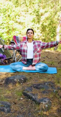 Sabah ormanının nefesiyle rahatla. Genç bir kadın sabah çam ormanında meditasyon yapıyor. Düşüncelerinle ve doğanla yalnızlık. Akıl sağlığına giden yol olarak doğa. Yavaş çekim dikey 4k