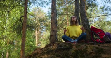 Doğayla bütünlük ve ormanda meditasyon. Genç bir kadın sabah çam ormanında meditasyona başlıyor. Düşüncelerinle ve doğanla yalnızlık. Ruh sağlığına giden yol olarak doğa.