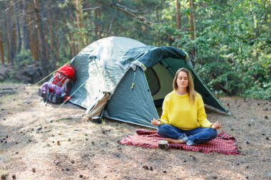 Sabah ormanıyla nefes al ve zihnini meditasyonla özgür bırak. Genç bir kadın sabah çam ormanında meditasyon yapıyor. Düşüncelerinle ve doğanla yalnızlık.