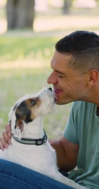 Akıl sağlığı için evcil hayvanlara bayılırım. Jack Russell Terrier köpeği olan orta yaşlı bir adam. Yavaş çekim dikey 4k görüntü.