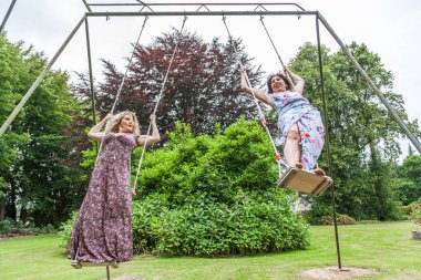 Güzel orta yaşlı birkaç bayan arkadaş Fransız parkında salıncakta sallanıyor.