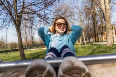 Bir bankta karın kaslarını çalıştıran genç bir kadının portresi - sağlık konsepti