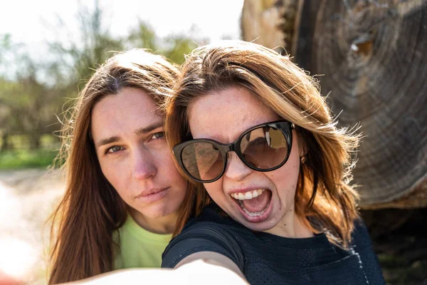 couple of pretty friendly women taking a selfie making funny faces