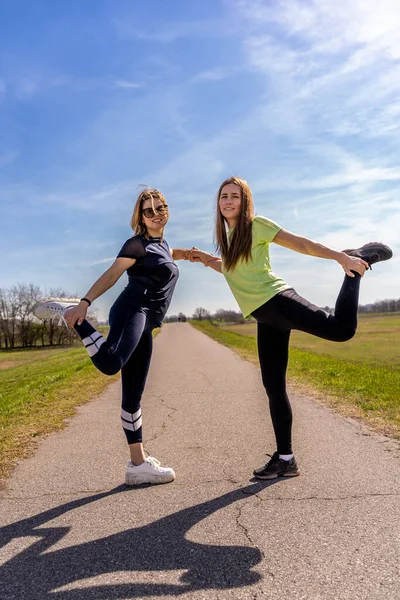 屋外で体操をするかなり運動能力のある女性のカップル ウェルネスコンセプト — ストック写真