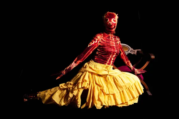 sensual woman dressed in a skeleton costume posing wearing a yellow skirt on a black background - halloween concept